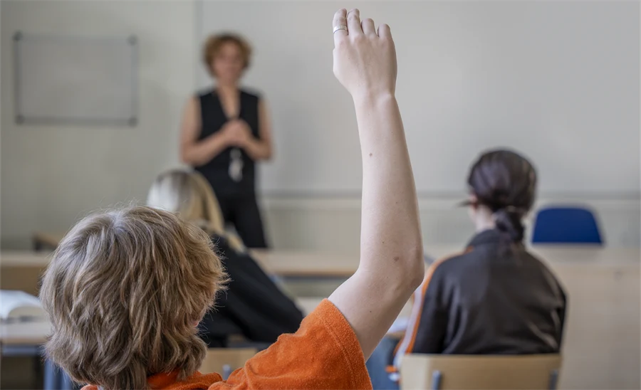 Ungdomen räcker upp en hand i klassrummet.