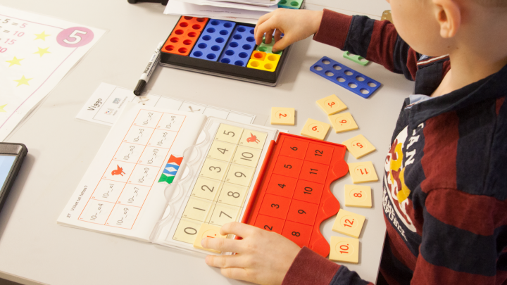 Bilden visar en elev som räknar matematik med hjälp av olika läromedel.