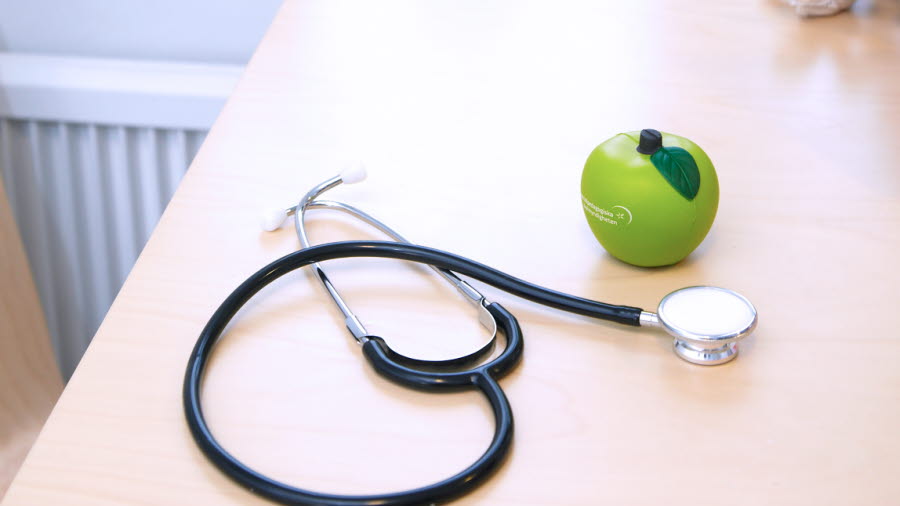 Ett stetoskop och ett äpple på ett bord.