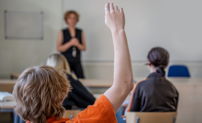 Ungdomen räcker upp en hand i klassrummet.