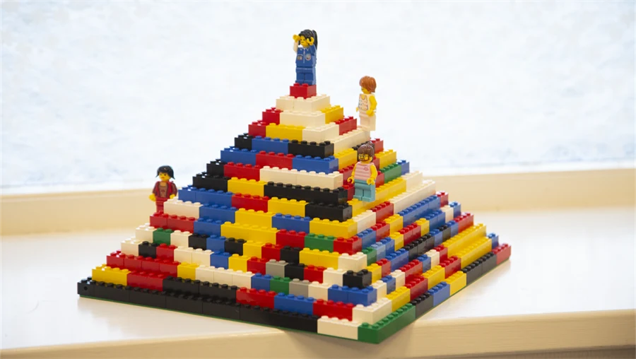En pyramid byggd av lego i olika färger, på olika ställen i den står legofigurer